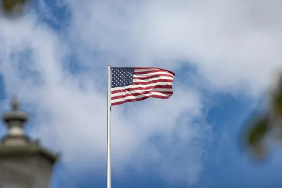 Flag of the United States with cloudy sky background.