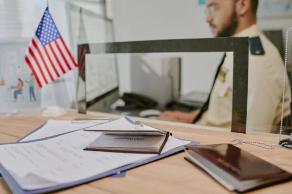 Close up of documents and passport on desk with American flag in background